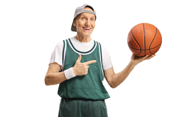 Cheerful elderly man holding a basketball and pointing isolated on white background - Foto, immagini