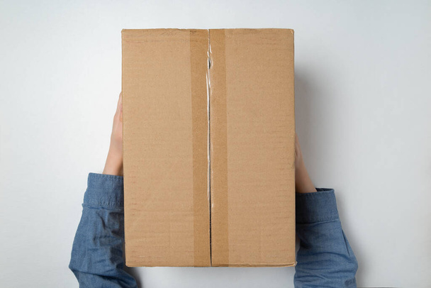 Дитячі руки тримають велику картонну коробку. Доставка посилок до домашньої концепції. Вид зверху
. - Фото, зображення