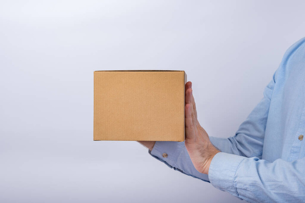 Hombre sosteniendo caja cuadrada de cartón sobre fondo blanco. espacio de copia. Fumar.
. - Foto, Imagen