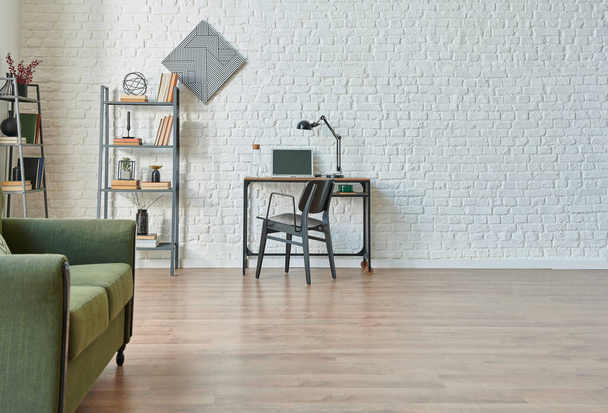 Μοντέρνο λευκό τούβλο τοίχο φόντο, πράσινο και γκρι καναπέ, μαύρο λεπτομέρεια επίπλων, τραπέζι εργασίας με βιβλιοθήκη. - Φωτογραφία, εικόνα