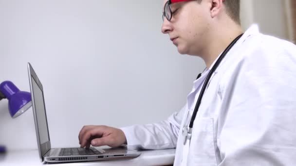 Lugar de trabajo de un médico. El terapeuta masculino trabaja en una computadora. El concepto de la medicina moderna y la tecnología utilizada por los profesionales médicos
 - Metraje, vídeo