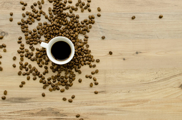 ?up of hot coffee, scattered coffee beans on a wooden light background. Romantic evening, breakfast, dinner. View from above.Place for text. Blurred background - Photo, Image