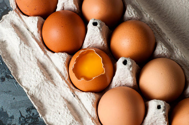 Uova di pollo in vassoio su sfondo scuro, tuorlo visibile
 - Foto, immagini