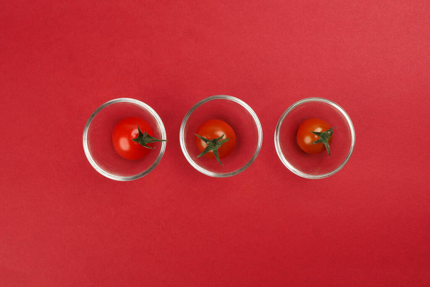 Pomodoro ciliegia maturo rosso con gambo su carta rossa sfondo copia spazio di testo mini ciotola di vetro
 - Foto, immagini