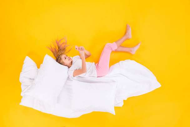Top view above high angle flat lay flatlay lie concept of her she nice cheerful focused girl lying on blanket using cell chatting isolated bright vivid shine vibrant yellow color background - Fotoğraf, Görsel