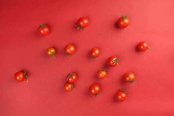 Czerwony dojrzały pomidor wiśniowy z łodygą na czerwonym papierze tło kopia przestrzeń tekstowa - Zdjęcie, obraz