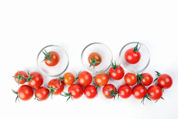 Czerwony dojrzały pomidor wiśniowy z łodygą na białym papierze tło mini szklanka miska kopia tekst przestrzeń granica linii - Zdjęcie, obraz