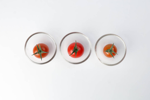 Rote reife Kirschtomate mit Stiel in Mini-Glasschale auf weißem Hintergrund - Foto, Bild