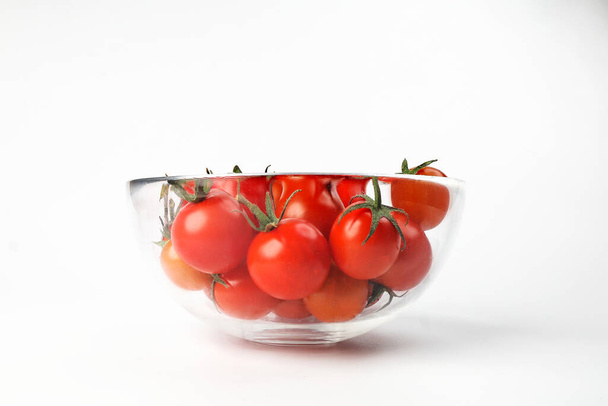 Czerwony dojrzały pomidor wiśniowy z miską ze szkła macierzystego na białym tle - Zdjęcie, obraz