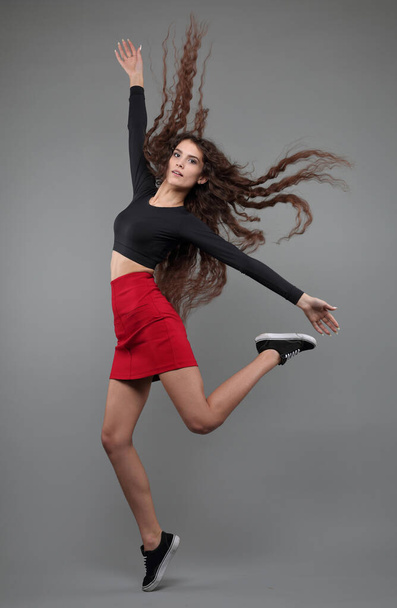 Studio growth portrait of a beautiful girl in a jump on a gray background - Foto, Imagem