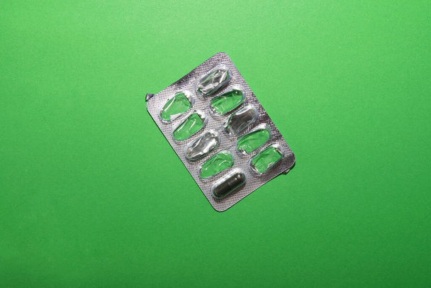 Packing with one unused pill lies on a green background - Photo, Image