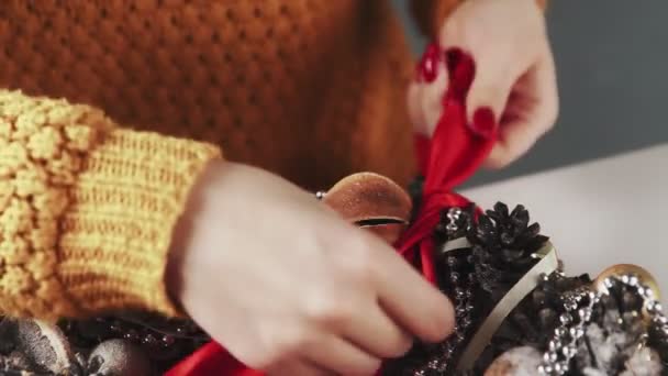 Αγνώριστη γυναίκα διακόσμηση στεφάνι Χριστούγεννα από κόκκινη κορδέλα - Πλάνα, βίντεο