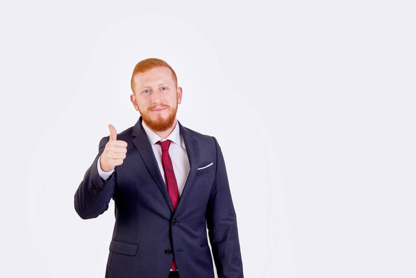 Redheaded businessman raising his thumb. He's wearing a red suit and tie - Valokuva, kuva