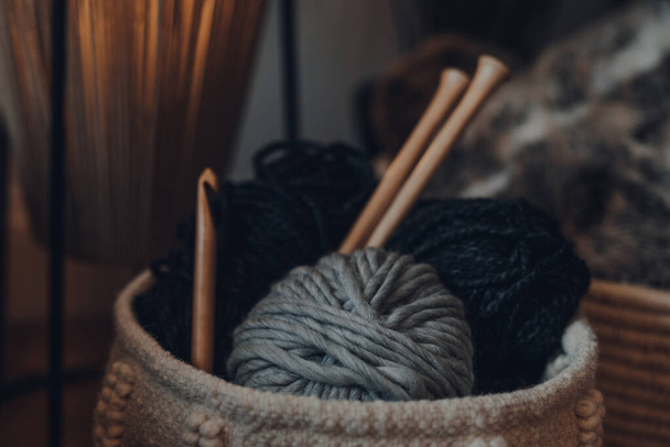Close up de bolas de fios dentro de uma cesta, com grandes agulhas de tricô de madeira, foco raso
. - Foto, Imagem