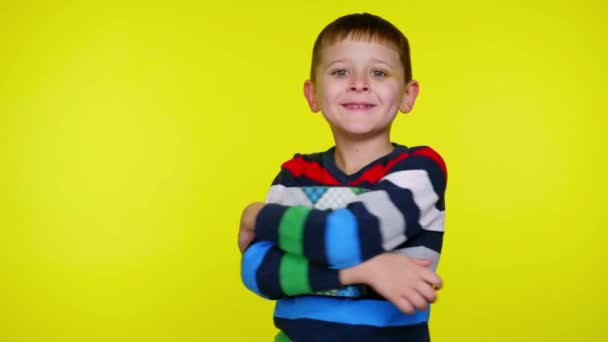 Fröhlicher kleiner Junge umarmt Schachtel mit Geschenk und lächelt auf gelbem Hintergrund - Filmmaterial, Video