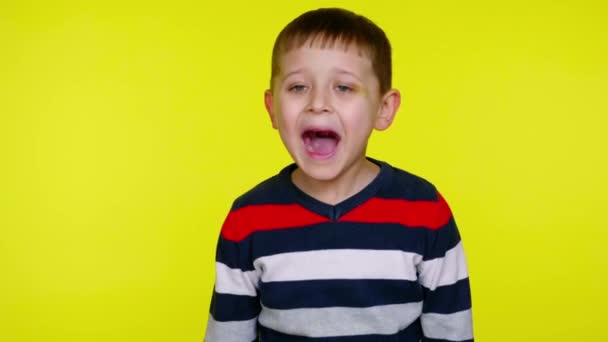 Mały chłopiec krzyczy na żółtym tle z przestrzenią do kopiowania - Materiał filmowy, wideo