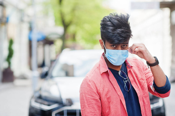 Coronavirus covid-19 concept. South asian indian man wearing mask for protect from corona virus posed against business car. - Фото, зображення