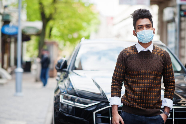 Coronavirus covid-19 concept. South asian indian man wearing mask for protect from corona virus posed against business car. - Φωτογραφία, εικόνα