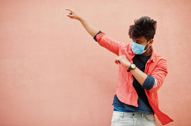 Coronavirus covid-19 concept. South asian indian man wearing mask for protect from corona virus isolated on pink background. - Фото, зображення