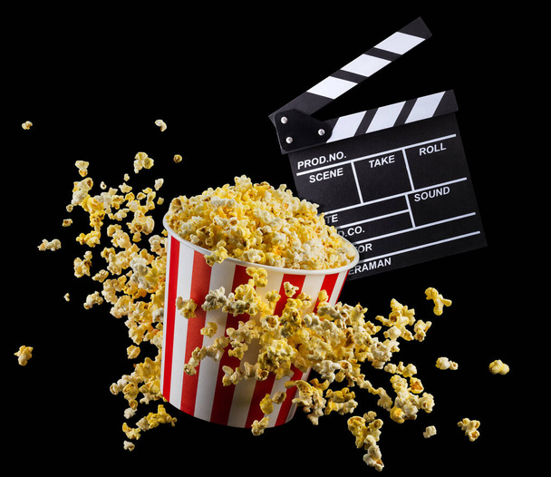 Flying popcorn and film clapper board isolated on black background - Photo, Image