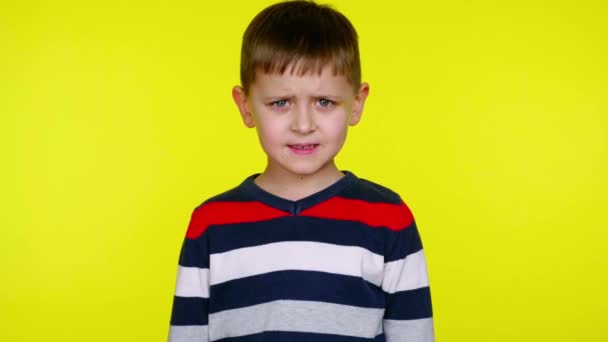 Angry little boy growls at the camera on a yellow background with copy space - Footage, Video