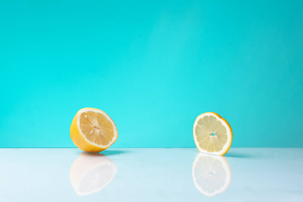 Половина лимона и ломтик с бирюзовым фоном и отражением
. - Фото, изображение