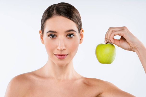 Beauty portrait of smiling young topless woman showing green apple while standing isolated over white background - 写真・画像