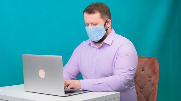 Caucasian adult bearded man works at home. Lifestyle concept photo with copy space. picture with a handsome guy who uses a protective mask. - Φωτογραφία, εικόνα