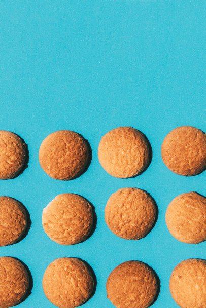 Top view of tasty butter cookies lined up isolated on a blue background with copy space. - Fotó, kép