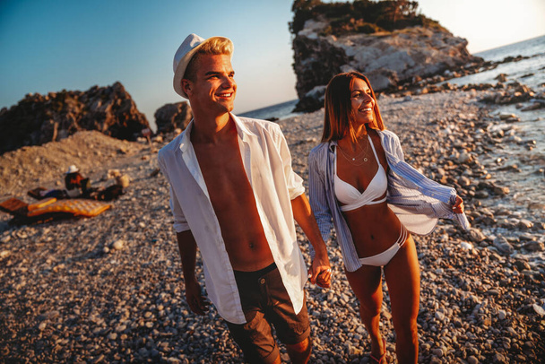 Happy romantic couple enjoying beautiful sunset walk on the beach. Travel vacation lifestyle concept - Photo, Image