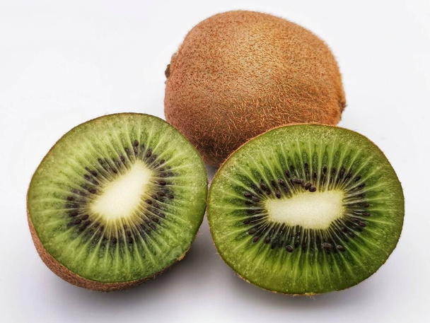 Studiofoto von zwei Kiwi-Früchten, eine halbiert mit weißem Hintergrund. - Foto, Bild