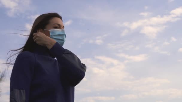 The beautiful woman takes off the medical mask outdoor. slow motion - Footage, Video