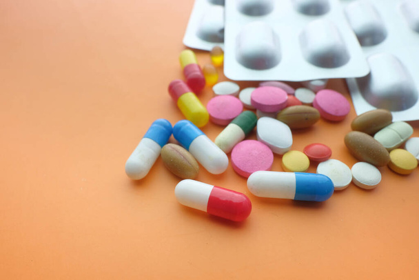  colorful pills and blister pack on orange background  - Foto, afbeelding
