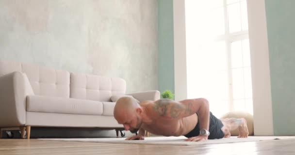 Athletic young shirtless man in shorts doing push-ups in living room at home. - Filmmaterial, Video