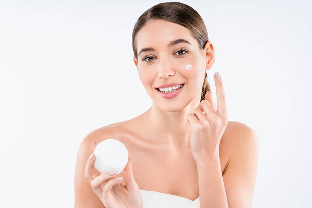 Beautiful young woman gets cream on her face. Skin care concept - Foto, Imagen