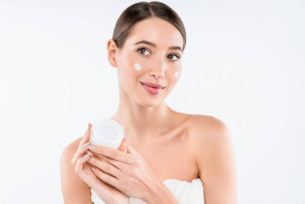Cute woman holding cream jar and applying it on her skin isolated on white background - Φωτογραφία, εικόνα