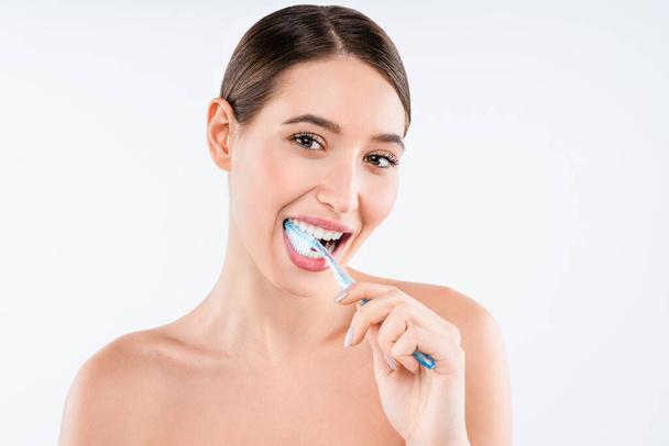 Caucasian girl in good mood using toothbrush on white background - Photo, image