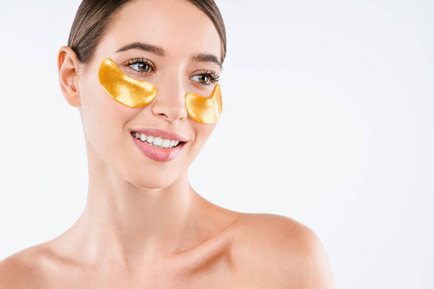 Beauty portrait of shirtless woman wearing cosmetic patches under her eyes isolated over white background - Foto, afbeelding
