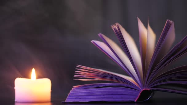 Poblíž otevřené knihy hoří svíčka a lítá barevný magický kouř. - Záběry, video