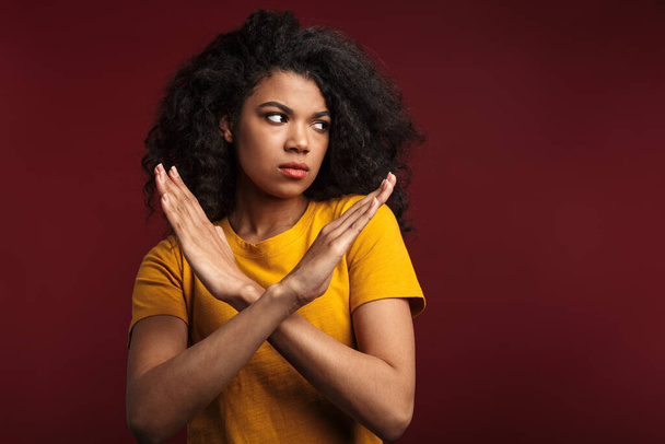 Image of outraged brunette african american woman crossing her arms and doing stop or denial gesture isolated over red background - Fotoğraf, Görsel