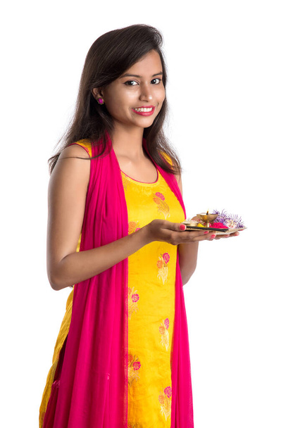 Beautiful Indian young girl holding pooja thali or performing worship on a white background - Фото, изображение