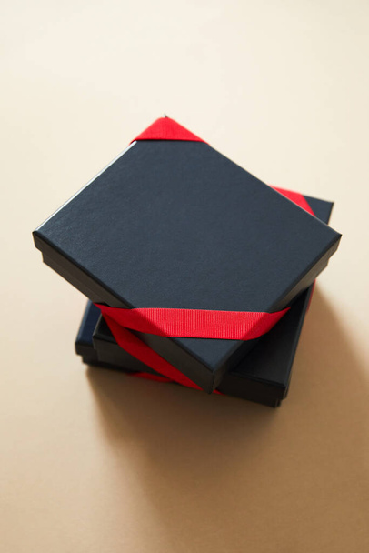 black gift boxes with red ribbons on beige background  - Valokuva, kuva