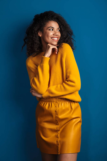 Image of a pretty happy positive optimistic young african woman posing isolated over blue wall background. - Foto, Imagem