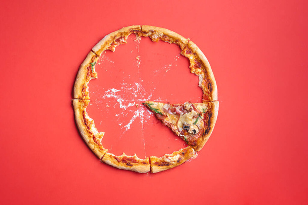Scheibe Pizza-Schinken auf rotem Papphintergrund, Draufsicht. Pizzareste und Brotkrumen. Das letzte Stück Pizza. - Foto, Bild