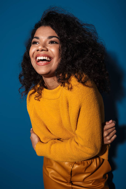 Photo of cheery laughing young african woman posing isolated over blue wall background. - Foto, imagen