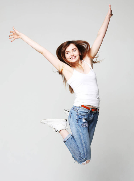 smiling young woman jumping in air over white background - Photo, image