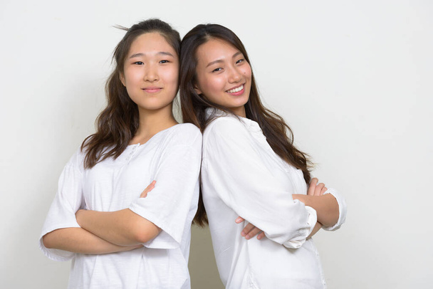 Estudio de dos jóvenes hermosas mujeres coreanas como amigas juntas sobre fondo blanco - Foto, Imagen