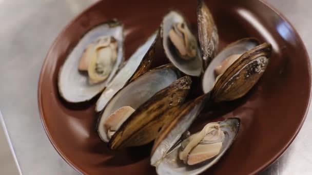 Tányér főtt kagyló snack. Friss kagyló barna tálban - Felvétel, videó