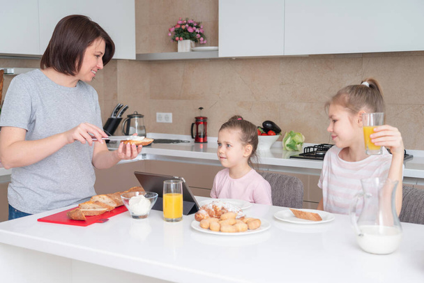 Madre y dos hijas desayunando juntas, feliz concepto de familia de madre soltera
 - Foto, imagen