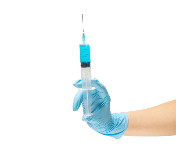 Female hand of a medic in a safe rubber glove of blue color in which a syringe with a liquid vaccine is blue, treatment of the disease. Isolate on a white background. - Fotó, kép